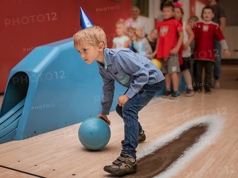 Six years old boy playing bowling during birthday party