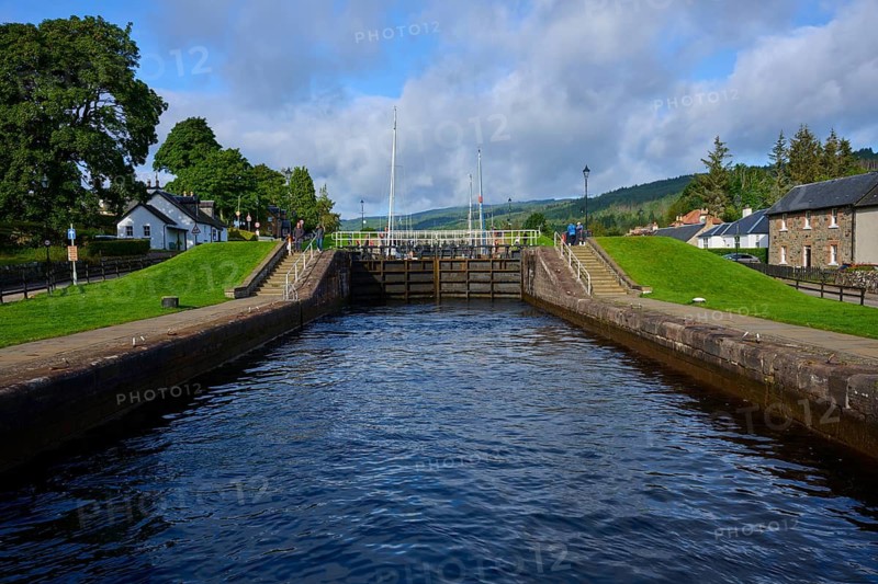 A canal with lock surrounded by trees and buildings in clear skies, Caledonian Canal, Fort Augustus, Loch Ness, Scotland, United Kingdom, Great Britain