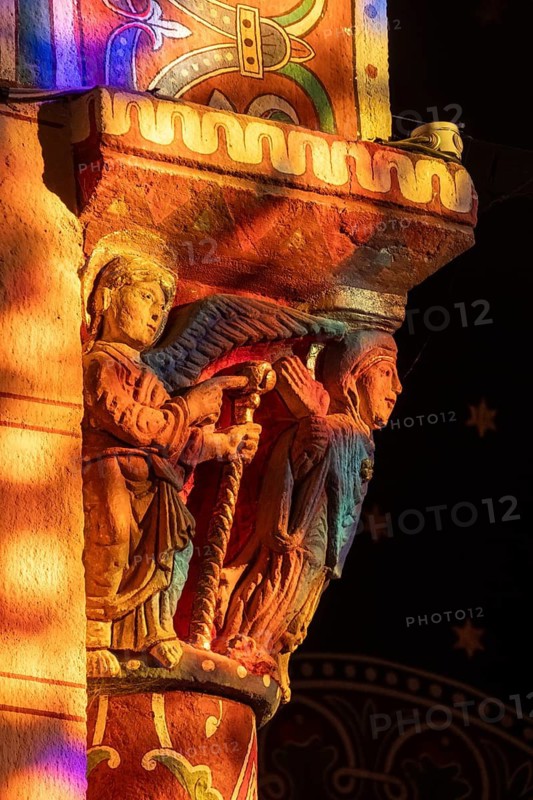 Issoire. Pillar (The Annunciation made to Mary) . The figures are illuminated by colorful light shining through a stained glass window inside Saint Austremoine Abbey, Puy de Dome, Auvergne Rhone Alpes, France