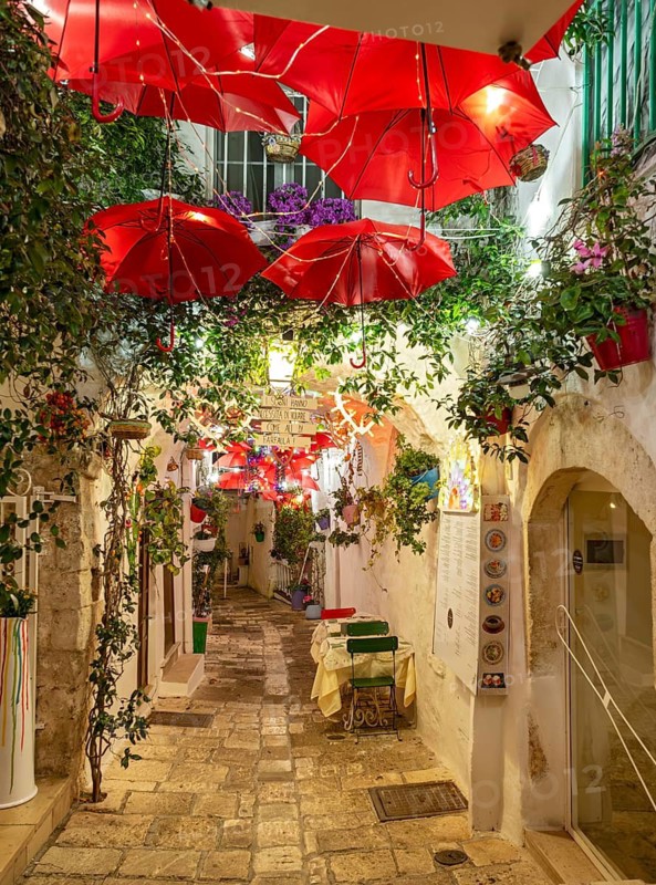 Narrow street in Ostuni lit by street lights at night, Apulia - Puglia, Italy