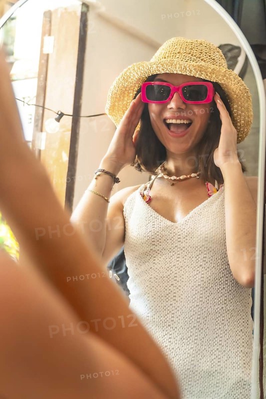 Happy tourist trying on pink sunglasses and straw hat, getting ready for a day at the beach in siargao island
