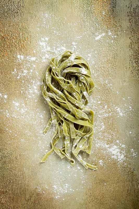 Raw tagliatelle pasta, with spinach, homemade, top view, no people, rustic style, cooking concept