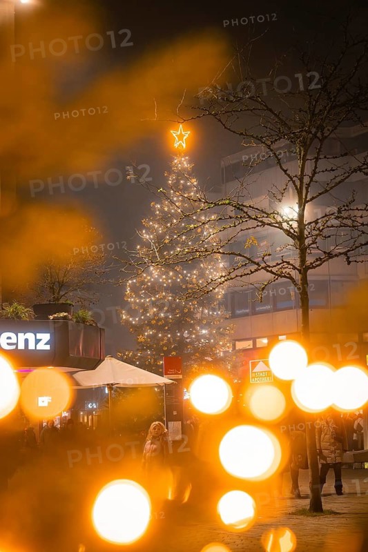 An illuminated Christmas tree in an urban environment with blurred lights, Christmas market, Nagold, Black Forest, Germany