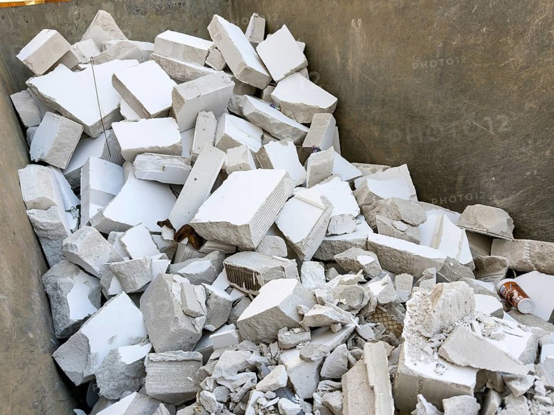 A large container is filled with construction waste from broken white porous concrete or gypsum building boards, Wuppertal, Germany