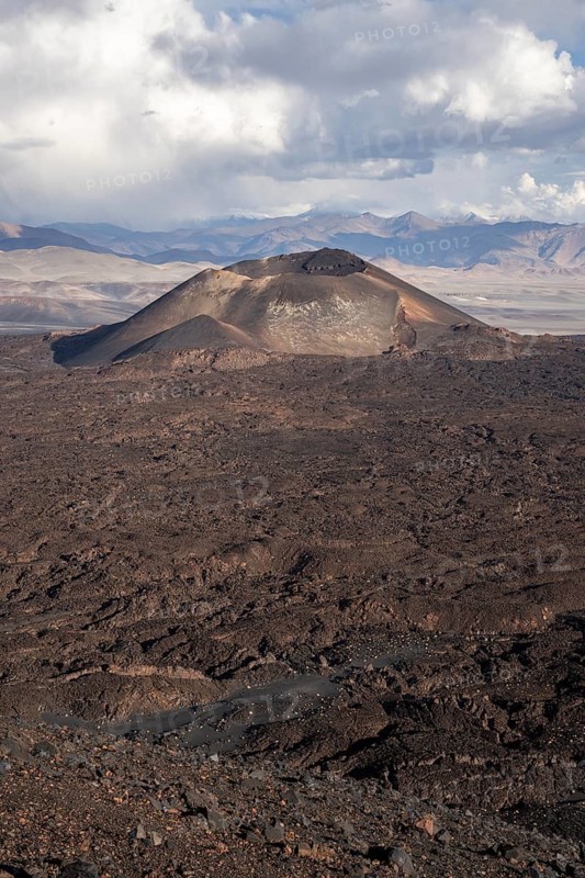 A volcano in a dry desert landscape under a cloudy sky, Argentina, volcanoes, lava field, Antofagasta