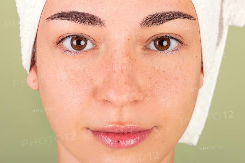 Close-up of a woman's clean, fresh face wrapped with a towel, representing beauty, self-care, and natural skin care routines in a serene and healthy environment