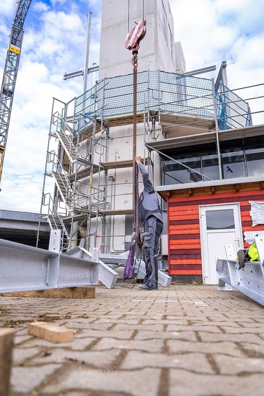Construction worker pulling a heavy object up a building with a crane, stairway extension to the new tower of the Calw central railway station onto the new track of the Hermann Hessebahn, Calw, Black Forest, Germany