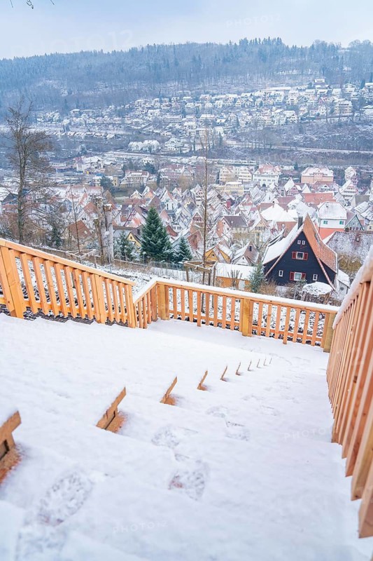 View of snow-covered village scenery from a snow-covered wooden staircase, New wooden footbridge in Calw city garden, Calw, Black Forest, Germany