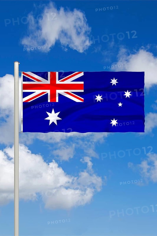 National flag of Australia, in front of cumulus clouds and blue sky, studio