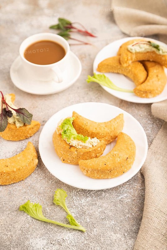 Homemade salted crescent-shaped cheese cookies, cup of coffee on brown concrete background and linen textile. side view, close up, selective focus