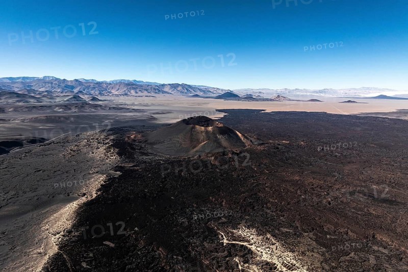 A breathtaking aerial view of Antofagasta Volcano in Catamarca, Argentina. The majestic volcanic landscape is surrounded by expansive desert plains under a vivid blue sky