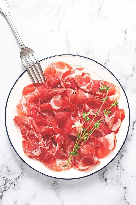 Plate with sliced cured meat, pork neck, prosciutto coppa, Italian delicacy