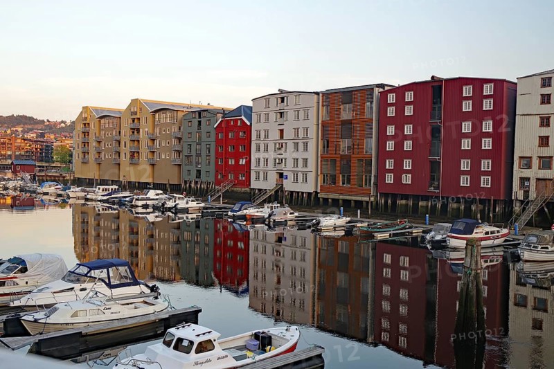 Colourful houses and boats are reflected in the calm harbor water in a peaceful evening mood, Nidelva, Trondheim, Tröndelag, Norway