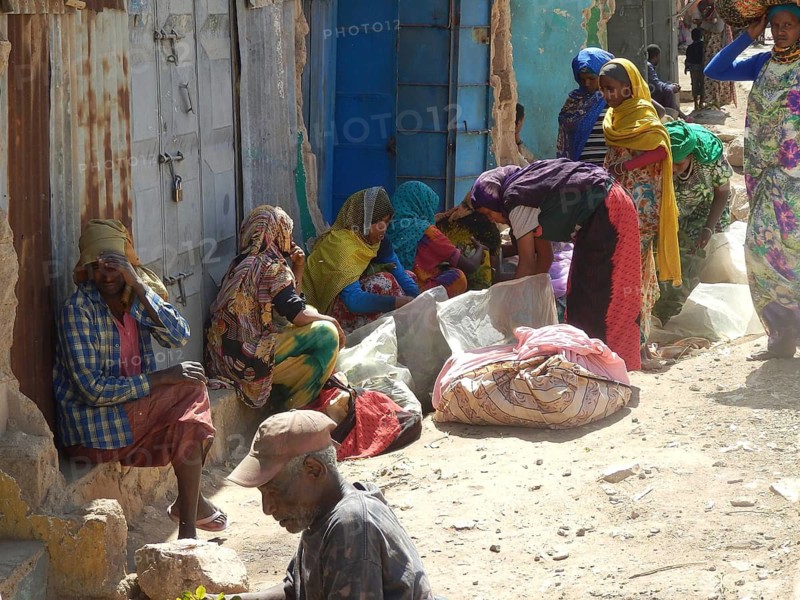 Market woman in traditional clothes sit and chat vividly in the shade on the side of the road, Harar, Ethiopia