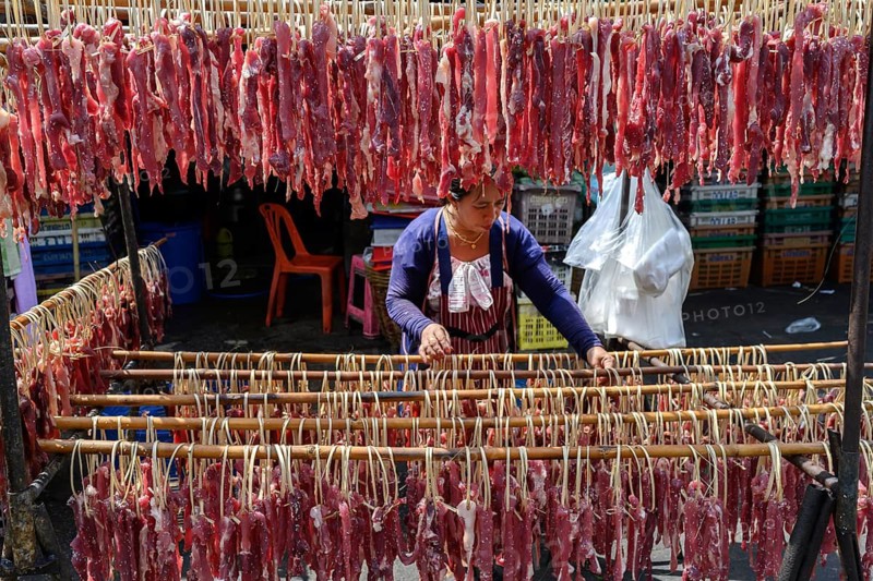 Bangkok, Thailand. February 19th 2025. A Thai woman hangs salted meat to dry in the sun at the Khlong Toei Market, Bangkok, Thailand, Asia