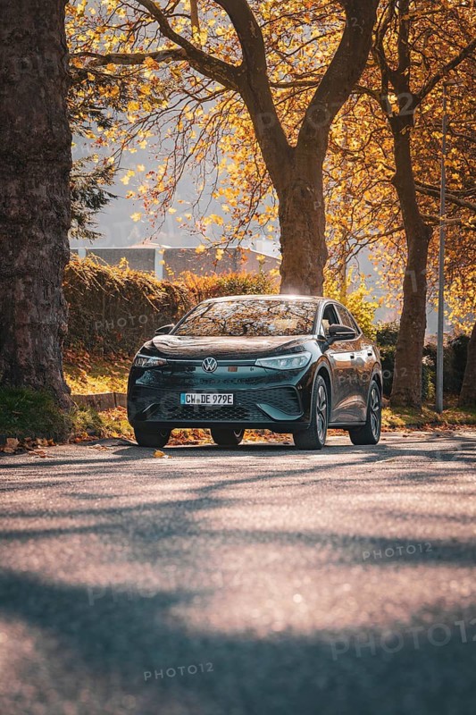 Car on autumn road flanked by sun and trees, electric car VW ID5, Deer Carsharing, Gechingen, Black Forest, Germany