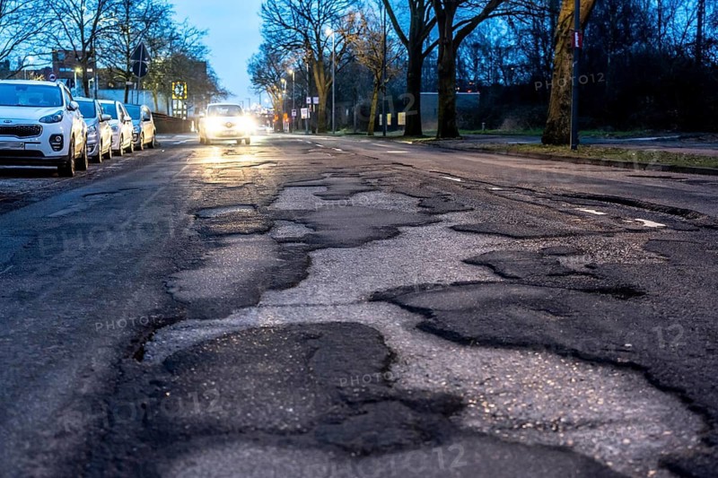 Many large potholes on an inner-city road, Lange Straße in Krefeld-Uerdingen, the heavily frequented road consists of more potholes than intact asphalt, road damage, vehicles can barely avoid, North Rhine-Westphalia, Germany