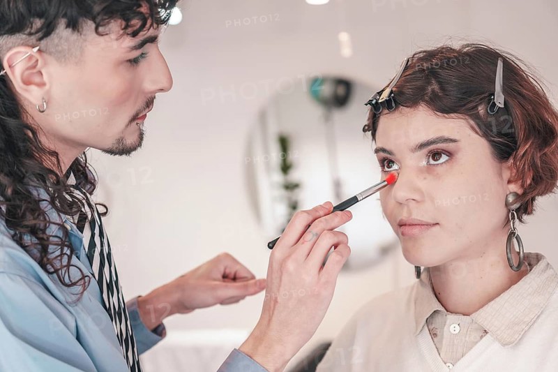 Professional makeup artist carefully applying foundation on a model's face using a brush, enhancing her natural beauty in a bright and modern beauty salon, promoting diversity and inclusion