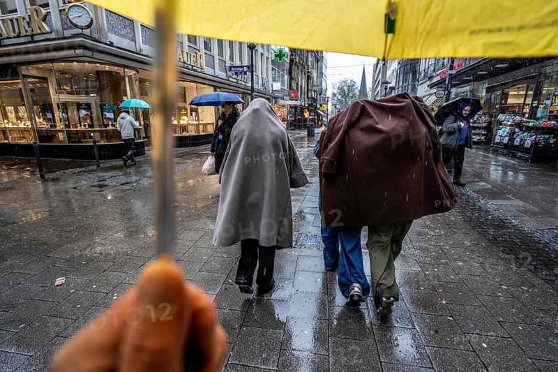 Passers-by in a pedestrian zone, Kettwiger Straße, young woman in rainy weather, without an umbrella, protecting themselves from the rain with coats and jackets, city center, Essen, North Rhine-Westphalia, Germany