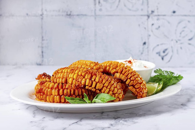 Corn ribs, with cream sauce, spices and lime, appetizer, on a white plate, homemade, no people