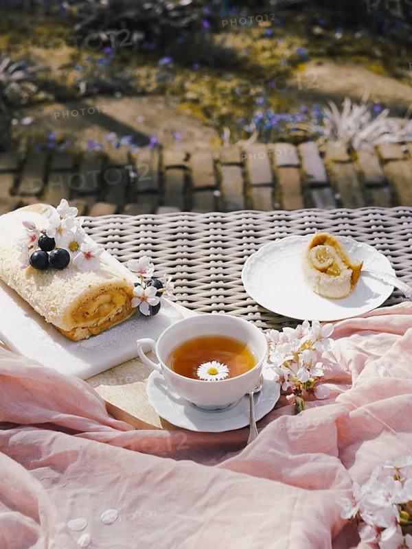 A delectable Swiss roll filled with rich dulce de leche, presented on a garden table, accompanied by tea and spring blossoms