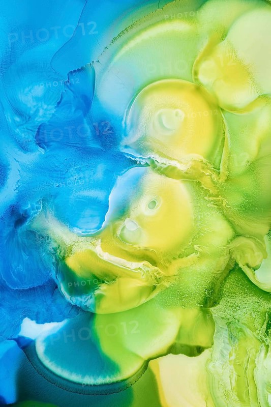 Vivid abstract artwork created by blending liquid inks in shades of blue, green, and yellow, forming an ethereal, fluid pattern that evokes a sense of movement and depth