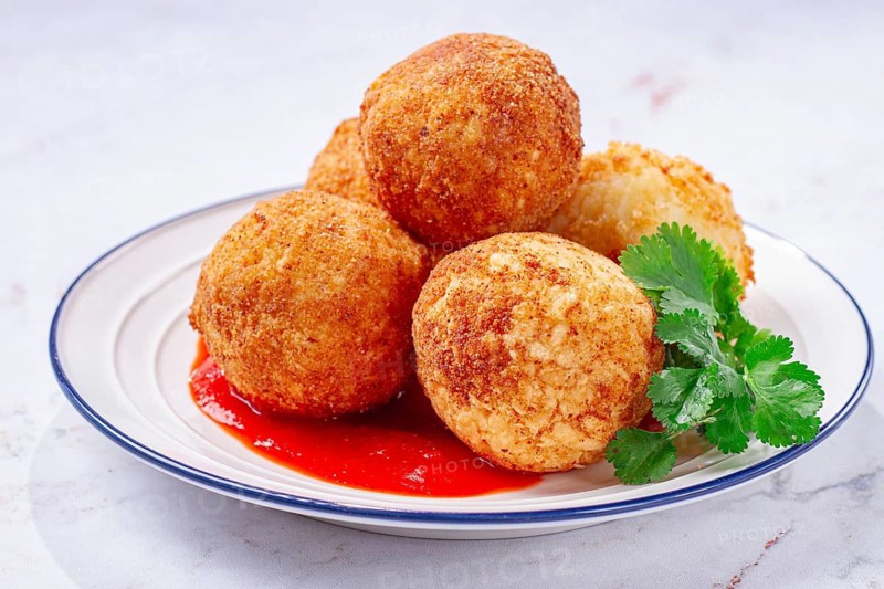 Arancini appetizer with tomato sauce, on a white plate, homemade, no people