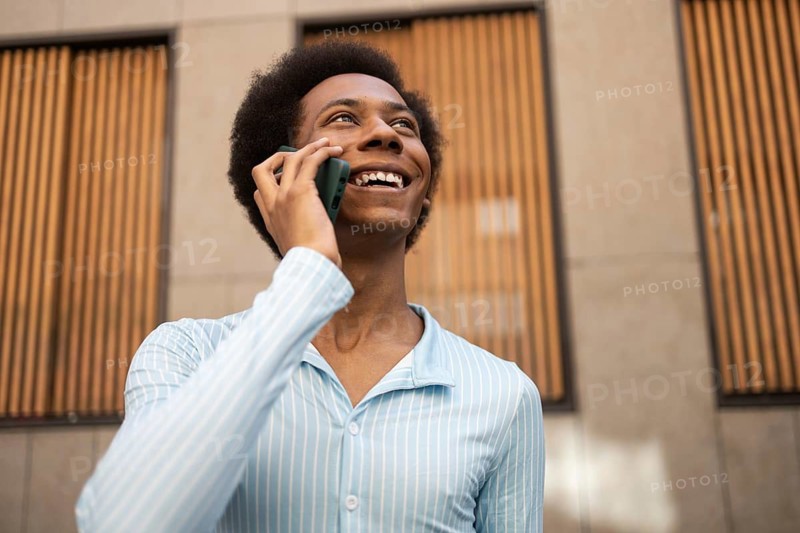 A joyful non-binary person talks on the phone outdoors, symbolizing identity, freedom, and pride. The image highlights diversity and inclusivity in a modern urban setting