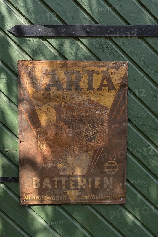Old rusted tin sign from Varta Batterien on a stable door, Bavaria, Germany