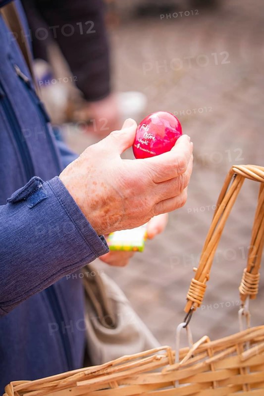 Hand holding a red egg over a basket on a paved road, Easter campaign, Sindelfingen, Böblingen district, Germany