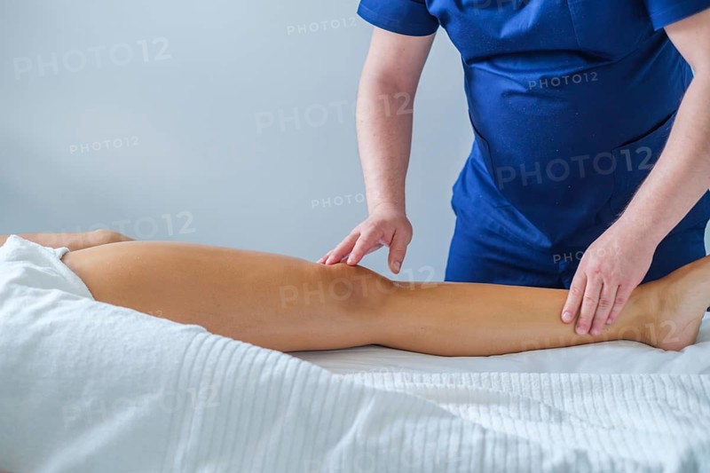 A woman enjoys a calming leg calf massage performed by a skilled therapist, promoting relaxation and wellness with gentle oil application