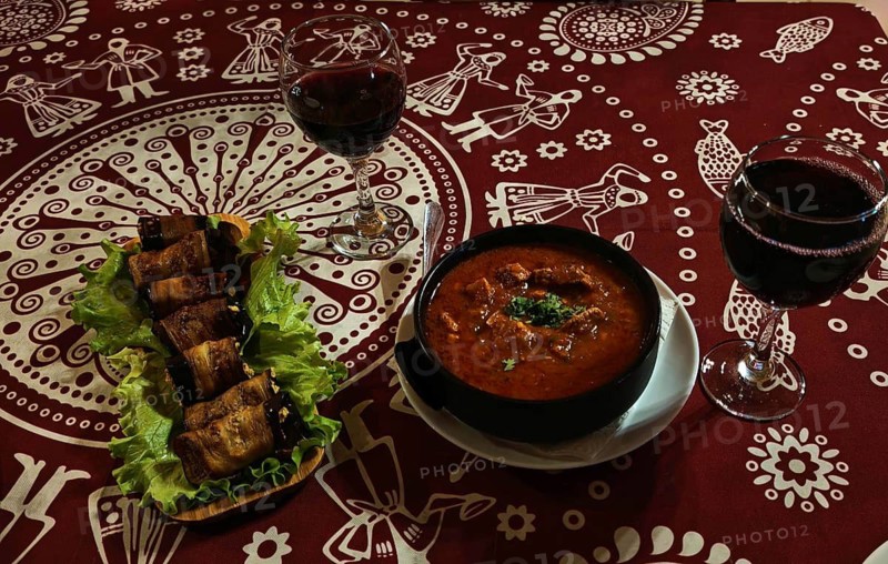 Table with traditional dishes, red wine and decorative tablecloth, Georgia