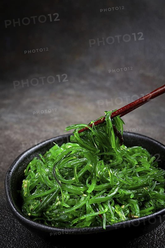 Chuka salad, made from fresh seaweed, with sesame dressing, served in a black bowl, with chopsticks