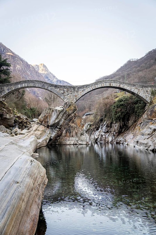 Scenic view of Ponte Dei Salti arching gracefully over the clear waters of the Verzasca River in Lavertezzo, Ticino, Switzerland. Stunning natural beauty and tranquility