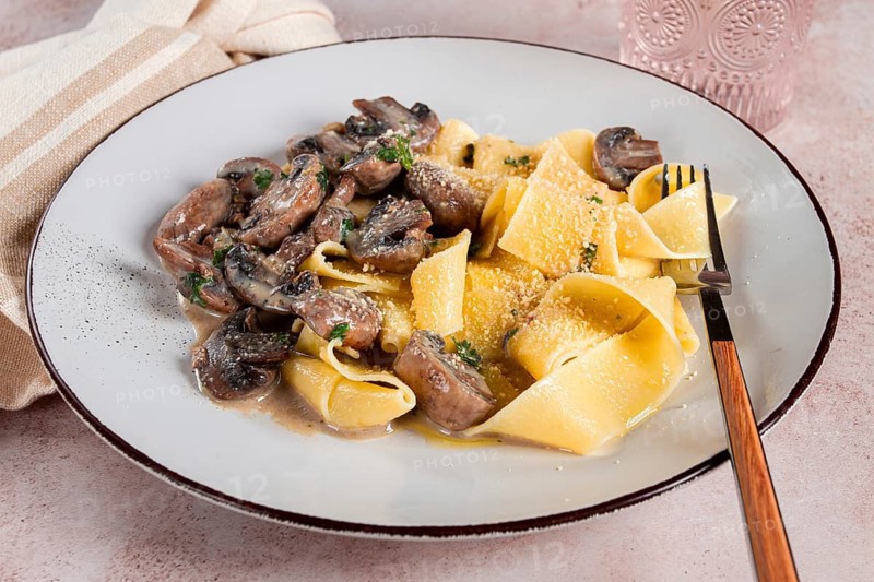 Delicious pappardelle pasta with mushrooms and cream served on a white plate