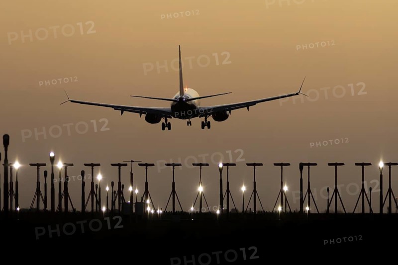 Boeing 737 commercial passenger airliner jet aircraft of Ryanair airways in flight on approach to land over runway lights at sunset at London Stansted airport, Essex, England, United Kingdom