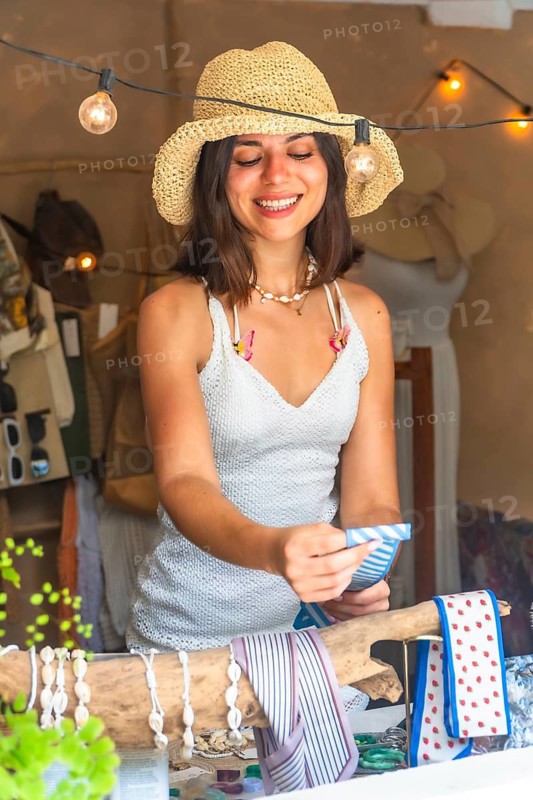 Young woman selling souvenirs at her shop in siargao island, philippines, holding a blue and white bandana