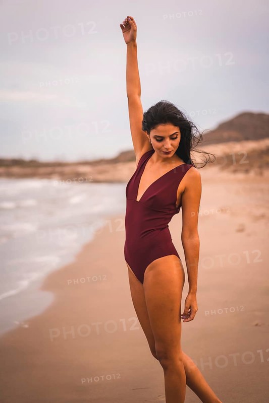 Young brunette Caucasian with a maroon swimsuit, cloudy afternoon in summer on the beach of Cabo de Gata, Nijar. Andalucia, Spain
