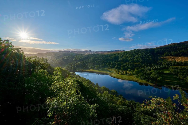 A lake in a green landscape illuminated by the rising sun, Queens View, Fincastle, Pitlochry, Scotland, United Kingdom, Great Britain