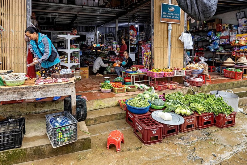 A lively market with various stalls full of fresh vegetables and fruit, people shopping, Asian atmosphere, selling meat and vegetables on the street in the Sa Pa area of Vietnam