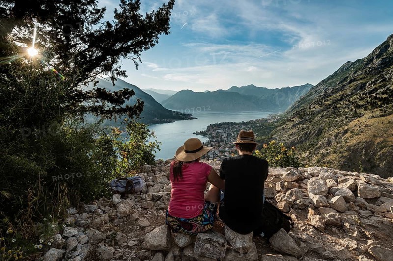 Couple seats on stones over Bay of Kotor, Montenegro.