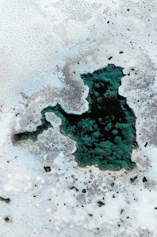 A captivating aerial view of salt ponds in La Puna, Argentina, showcasing diverse textures and vibrant turquoise hues. The image highlights the natural beauty and geological patterns