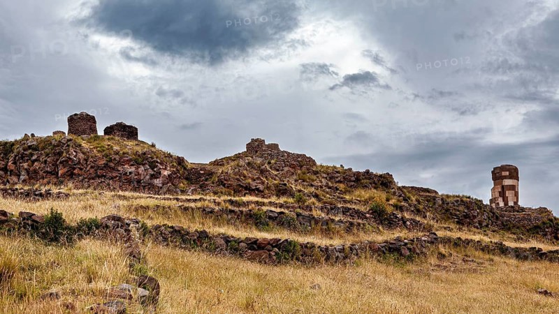 Ancient stone ruins on a grassy hill under a cloudy sky, The Chullpas of Sillustani near Puno in Peru