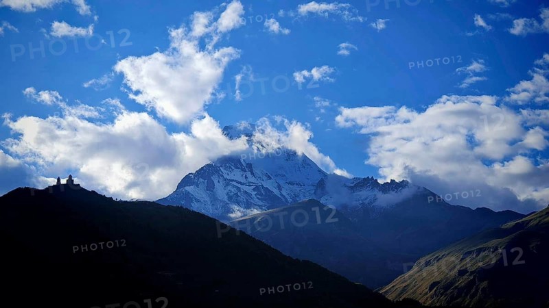 Snowy mountains with dramatic sky and clouds in the background Kazbek, Kazbegi, Stepantsminda, Georgia