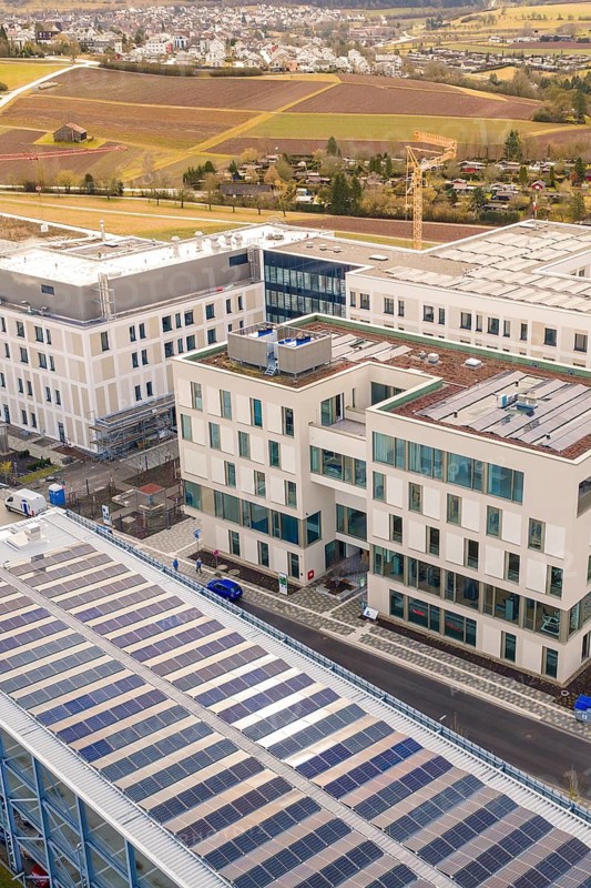 Modern buildings with solar systems, city in the background, surrounded by fields, shortly in front of opening, Calw health campus, Calw district, Germany