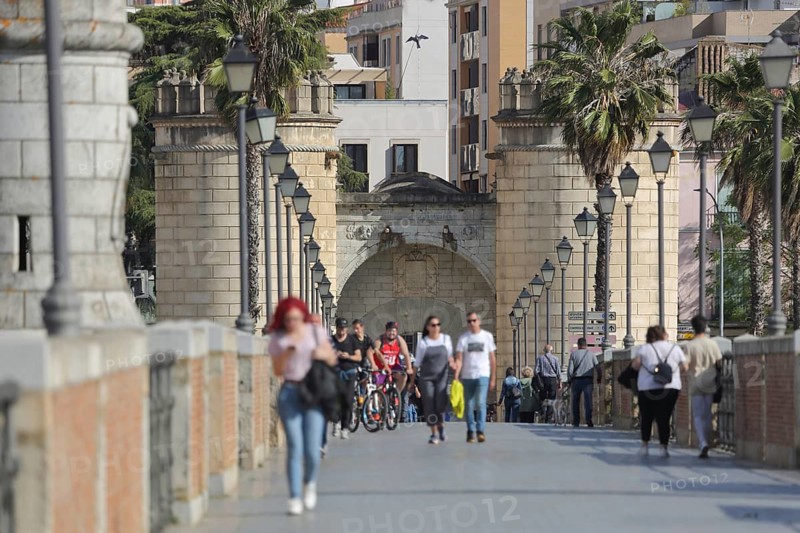 Pedestrians on the Puente de Palmas with a view of Puerta de Palmas, walkers strolling on bridge, city gate, landmark, depth blur, Badajoz, Extremadura, Spain