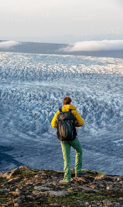 Young man, tourist in front of impressive glacier, in the evening light, glacier tongues Kötlujökull, Myrdalsjökull glacier Pakgil, Iceland
