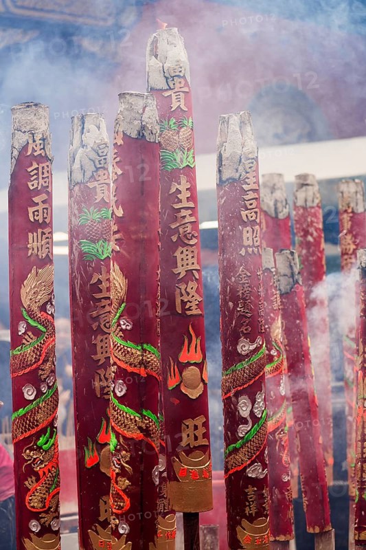 A vibrant display of large red incense sticks adorned with dragons and Chinese characters, emitting smoke during the Chinese New Year celebrations in Hong Kong