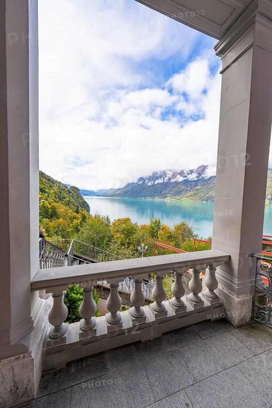 View from a terrace of a tranquil lake surrounded by mountains and clouds, Grandhotel Giessbach, Lake Brienz, Switzerland