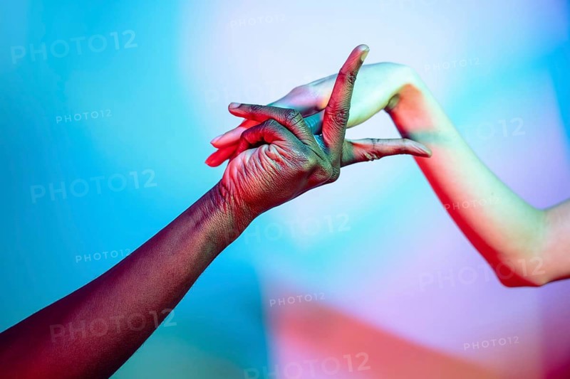 A close-up image of multiethnic hands gracefully intertwined against a vibrant backdrop. This artistic representation symbolizes unity, diversity, and the beauty of human connection